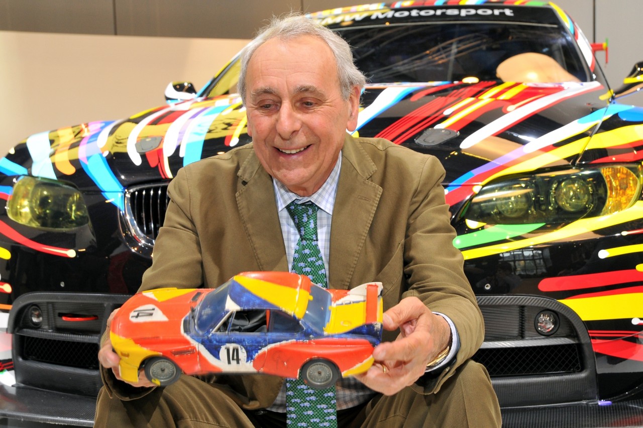 Hervé Poulain, Godfather of the Art Car Collection in front of the 17th BMW Art Car with a miniature of the first BMW Art Car by Alexander Calder in his hands (05/2010)